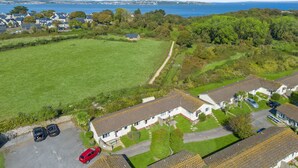 An aerial view of a residential area with houses, a large green field, and a body of water in the background. - No.1 Cottage is a charming and cosy South Devon holiday cottage (Brixham)