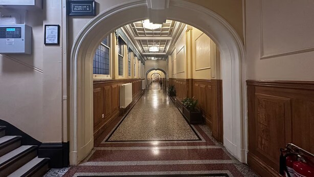 A hotel hallway with a central carpeted walkway, wooden paneling on the walls, and a sign indicating the location of the staircase. - Luxury Living at Charing Cross 26 | Best of London (London)
