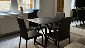 A room with a table and chairs, a radiator, a window with blinds, and a door. - Luxury Living at Charing Cross 26 | Best of London (London)