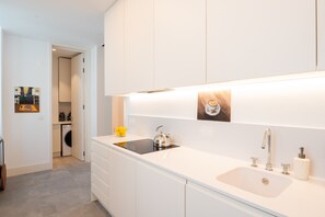 A modern kitchen with white cabinetry, a stainless steel kettle, a sink, and a small dish rack. - FLH Liberdade Balcony Apartment I (Lisboa ciudad)