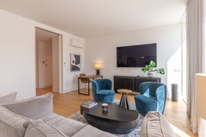 A modern living room with a sofa, two blue armchairs, a coffee table, a TV, and a potted plant. - FLH Liberdade Balcony Apartment II (Lisboa ciudad)