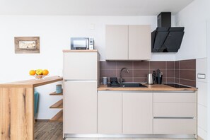 Eine moderne Küche mit Holzarbeitsplatte, einem eingebauten Backofen, einer Spüle und einer Mikrowelle.