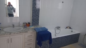 Un baño con lavamanos, espejo, tocador y bañera.