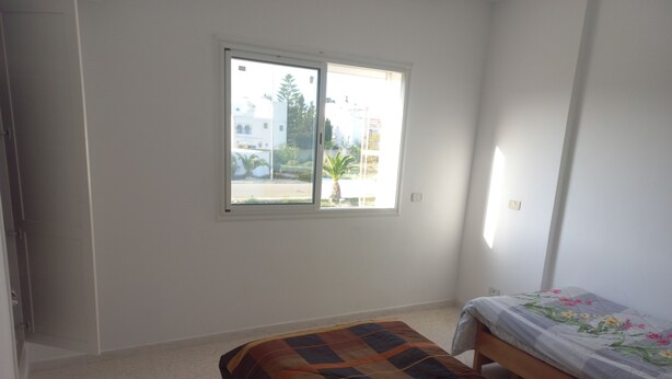 Un dormitorio con una cama individual, una ventana y una puerta.