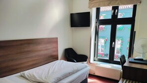 A hotel room with a bed, a desk, a chair, a TV, and a window with a view of the outside. - 1 Person Holiday Park Home in Aalborg (Aalborg)