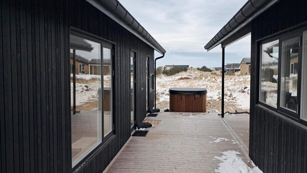 A corridor with wooden walls and large windows, leading to a hot tub area. - 4 Star Holiday Home in Lokken (Lokken)