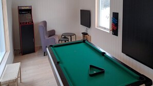 A pool table, a chair, a small table, a television, and a window in a room with wooden walls. - 4 Star Holiday Home in Lokken (Lokken)