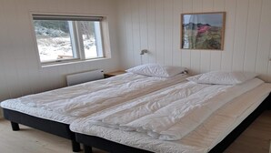 A bedroom with a large bed, a window, a wall-mounted light, and a framed picture. - 4 Star Holiday Home in Lokken (Lokken)