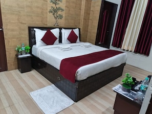 Ein ordentlich eingerichtetes Hotelzimmer mit einem Bett, einem Nachttisch, einem kleinen Tisch mit Pflanze und einem Fenster mit Vorhängen.