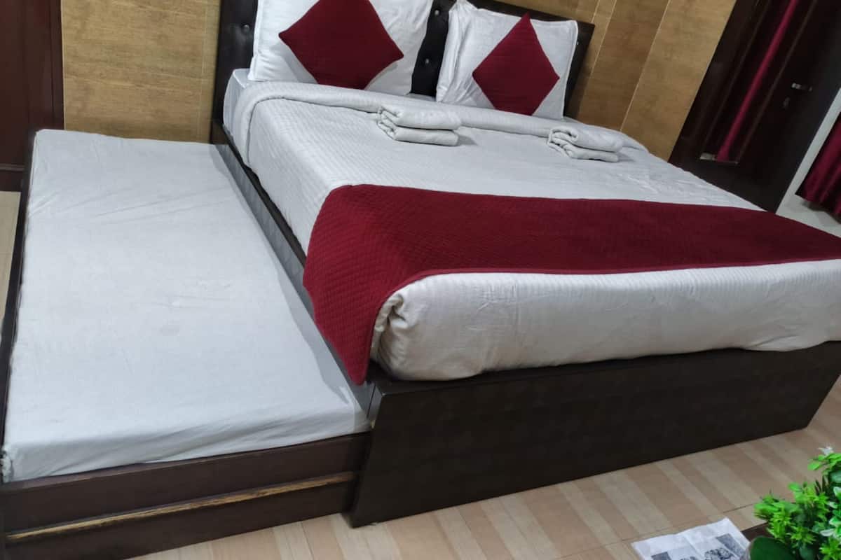 Uma cama com um cobertor vermelho, um travesseiro e outro combinando na cabeceira.