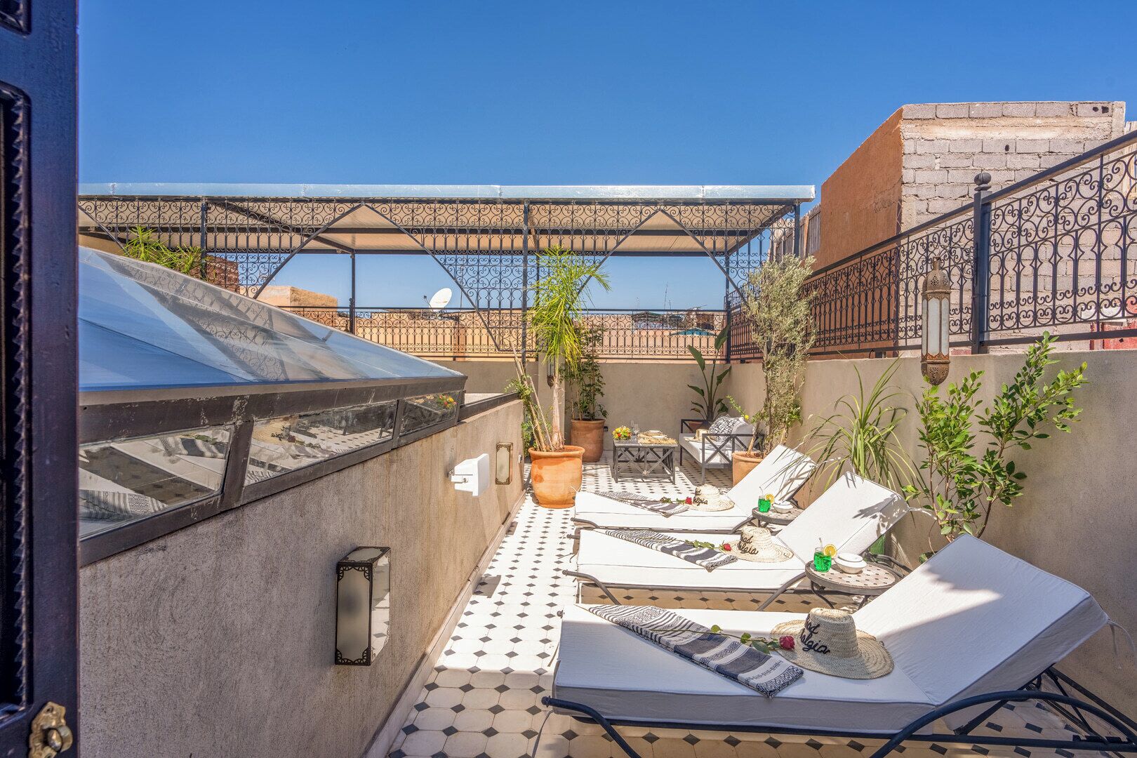 A rooftop terrace with outdoor seating, potted plants, and a pergola structure.