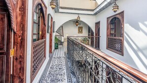 A corridor with ornate wooden doors, a tiled floor, and a glass ceiling. - Riad Nostalgia & Spa (Marrakech)