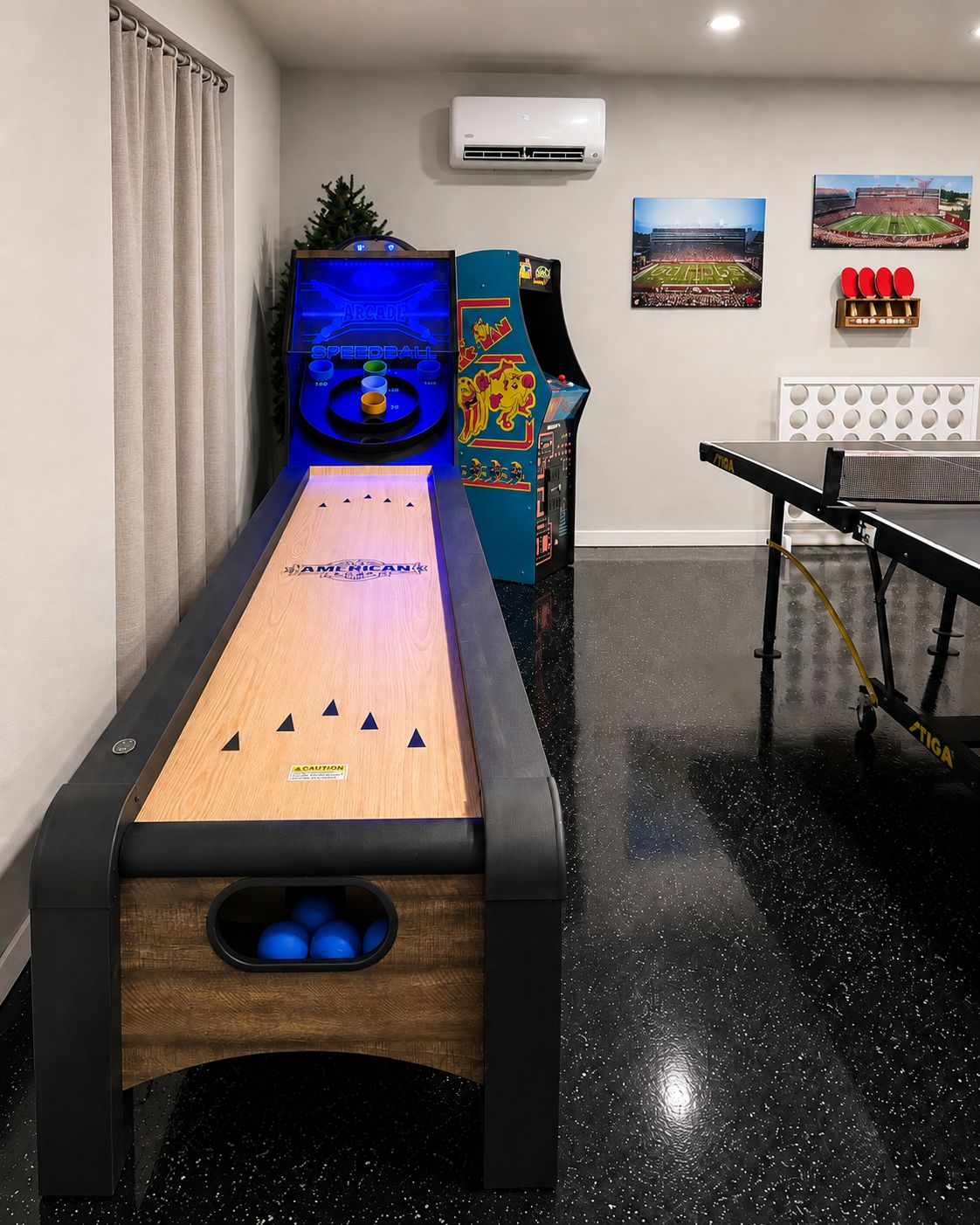 A billiards table with a wooden surface and a safety cover, a ping pong table, and a wall-mounted air conditioning unit.