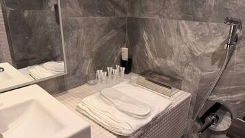 Un baño con lavamanos blanco, espejo, toallero y zona de ducha.