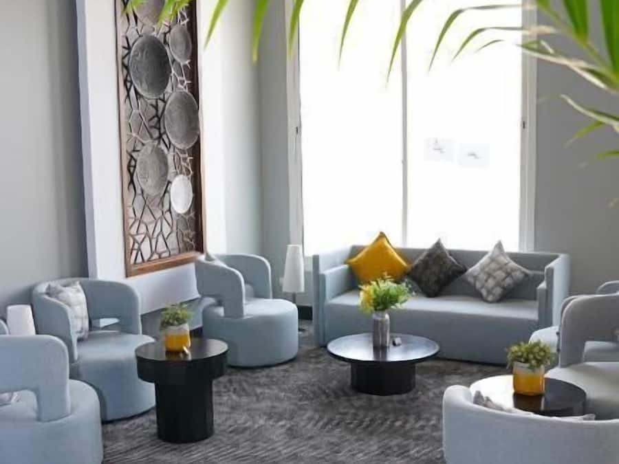 Ein modernes Wohnzimmer mit grauen Sofas, runden Couchtischen und einer dekorativen Wandverkleidung.