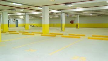 A multi-level parking garage with yellow and white painted columns, clear lane markings, and emergency equipment.