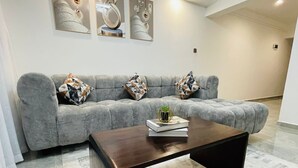 Uma sala de estar moderna com um sofá cinza, uma mesa de centro de madeira e arte abstrata na parede.