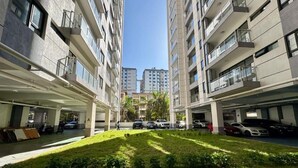 Estacionamento de vários andares com carros estacionados em ambos os lados, área gramada no centro e céu claro acima.