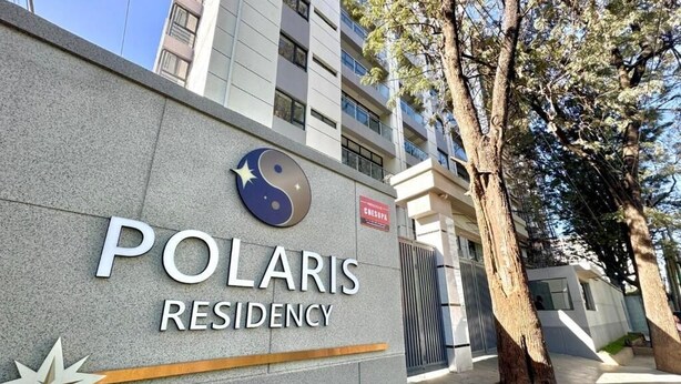 Um edifício com uma placa indicando 'POLARIS RESIDENCY' e um emblema de estrela.