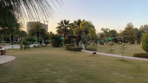 Un parc avec de l’herbe, des arbres, un sentier et un kiosque.