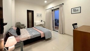 Ein Schlafzimmer mit Bett, Schreibtisch, Stuhl, Deckenventilator, Fenster mit Vorhängen und einem motivierenden Zitat an der Wand.