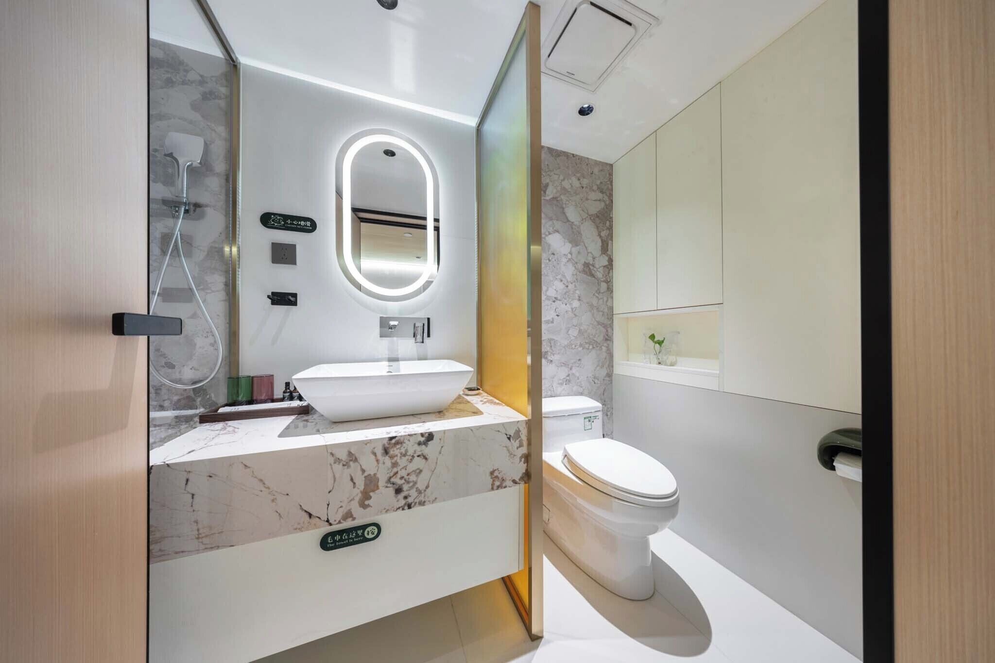 A modern bathroom with a marble sink, a toilet, and a shower.