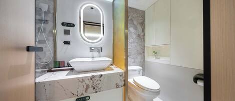 A modern bathroom with a marble sink, a toilet, and a shower.