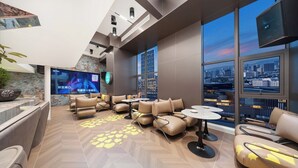 Un hall d’hôtel moderne doté d’un grand écran de télévision, de sièges confortables et offrant une vue sur la ville.