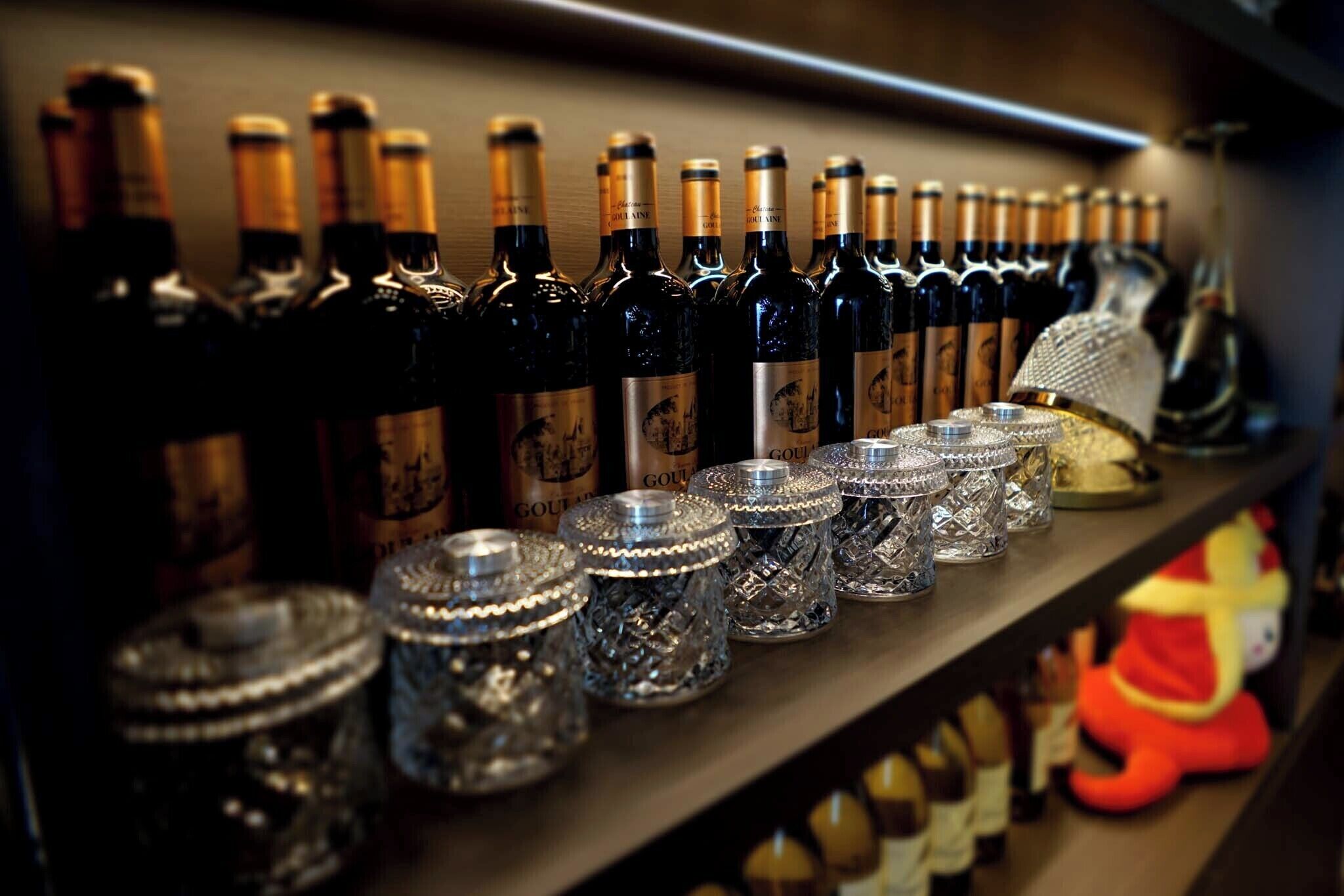 A shelf with multiple wine bottles and crystal decanters.