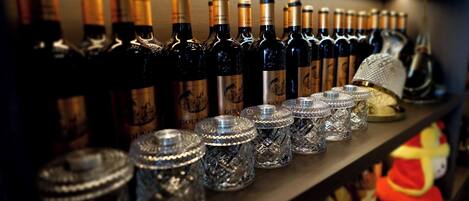 A shelf with multiple wine bottles and crystal decanters.