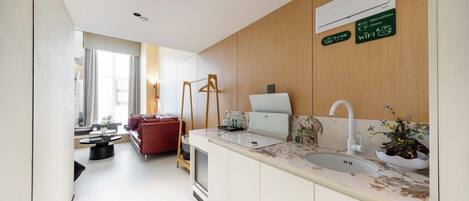 A modern kitchen with a sink, countertop, and wooden paneling.