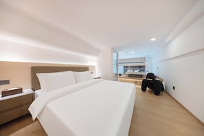 A modern hotel room with a large bed, a nightstand, a desk, and a chair.