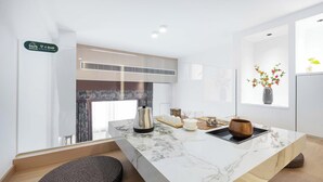 Une cuisine moderne avec un plan de travail en marbre, une bouilloire, un vase de fleurs et un panneau indiquant la présence d’un restaurant.