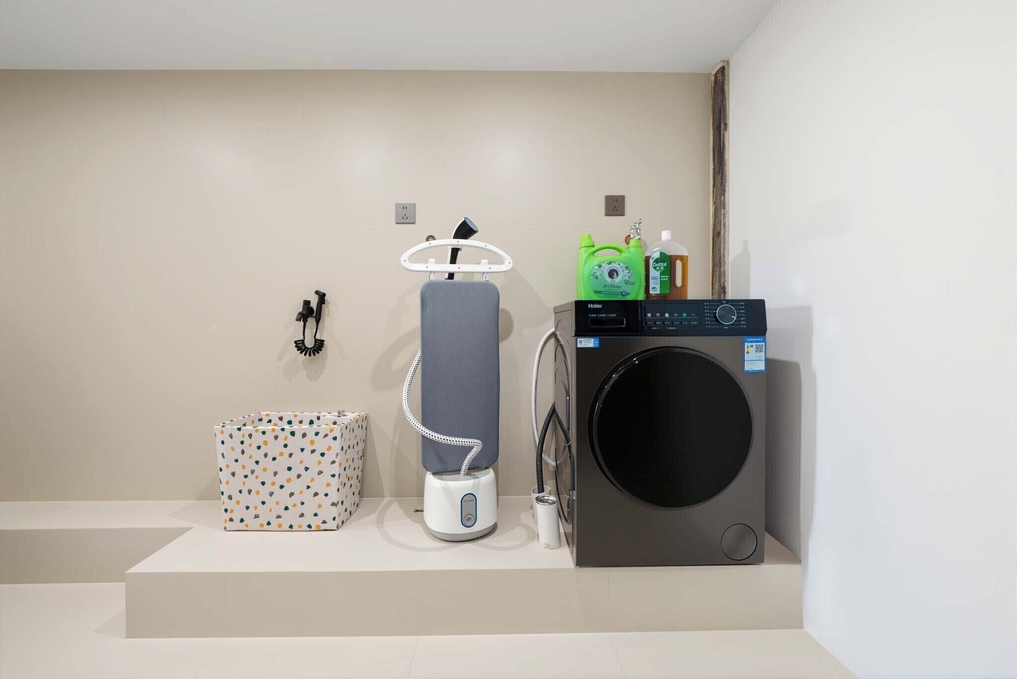 A modern bathroom with a washing machine, a hairdryer, and a small storage box.
