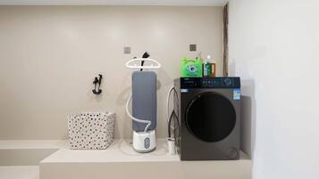 A modern bathroom with a washing machine, a hairdryer, and a small storage box.