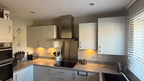 Una cocina moderna con electrodomésticos de acero inoxidable, armarios blancos e iluminación debajo de los armarios.