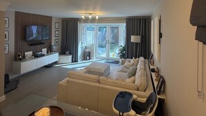 Una sala de estar moderna con un sofá, una mesa de centro, un televisor y una lámpara de techo.