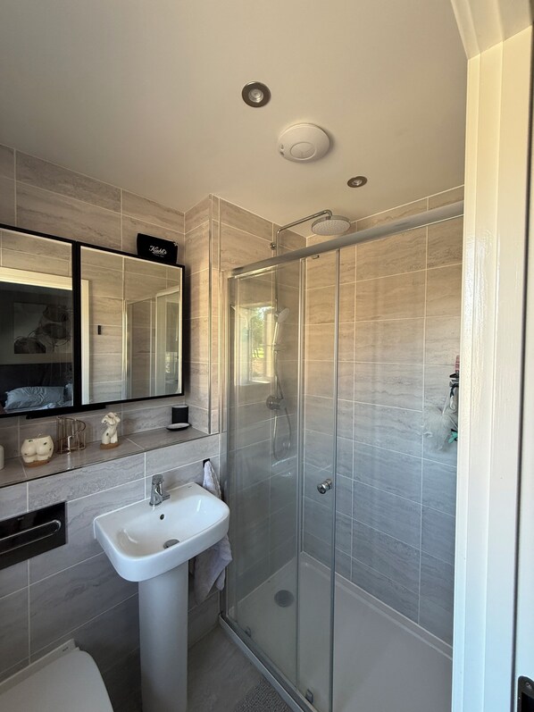 A modern bathroom with a glass-enclosed shower, a white sink, and a large mirror above the sink. - Beautiful family home in stunning Yorkshire village between York and Leeds (Tadcaster)