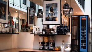 Interior de una cafetería moderna con una máquina de café, cuencos con cereales y banderas escandinavas.