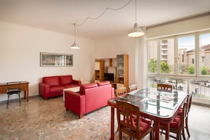 Ein Wohnzimmer mit einem roten Sofa, einem Glastisch und einem Fernseher.