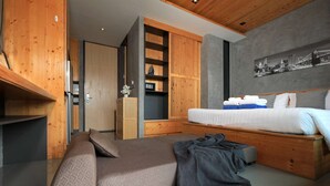 Un dormitorio moderno con una cama, un sofá, un armario de madera y un cuadro con un paisaje urbano.