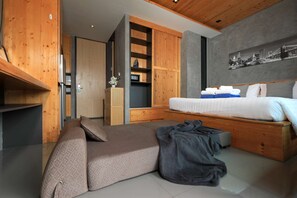 Ein modernes Schlafzimmer mit einem Bett, einer Couch, einem Holzschrank und Wandbild mit Stadtansicht.