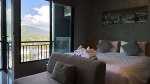 Quarto de hotel com uma cama, um sofá, vista para a paisagem urbana e uma varanda.