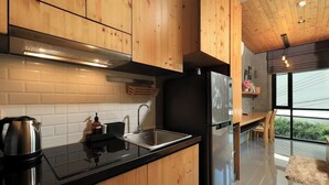 Eine moderne Küche mit Holzschränken, einer schwarzen Arbeitsplatte, Edelstahlgeräten und einem großen Fenster mit Blick.