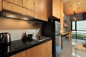 Eine moderne Küche mit Holzschränken, einer schwarzen Arbeitsplatte, Edelstahlgeräten und einem großen Fenster mit Blick.