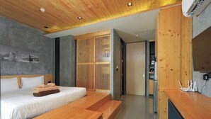 Ein modernes Hotelzimmer mit einem hölzernen Bett, einem Schreibtisch mit Computer und Blick auf die Stadt.