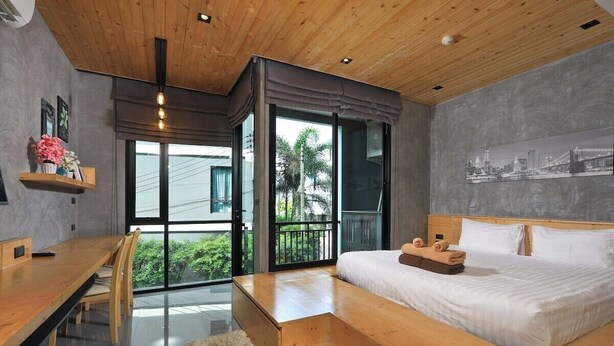 Ein modernes Schlafzimmer mit Holzboden, einem großen Bett, einem Esstisch und Blick durch die Glastüren.