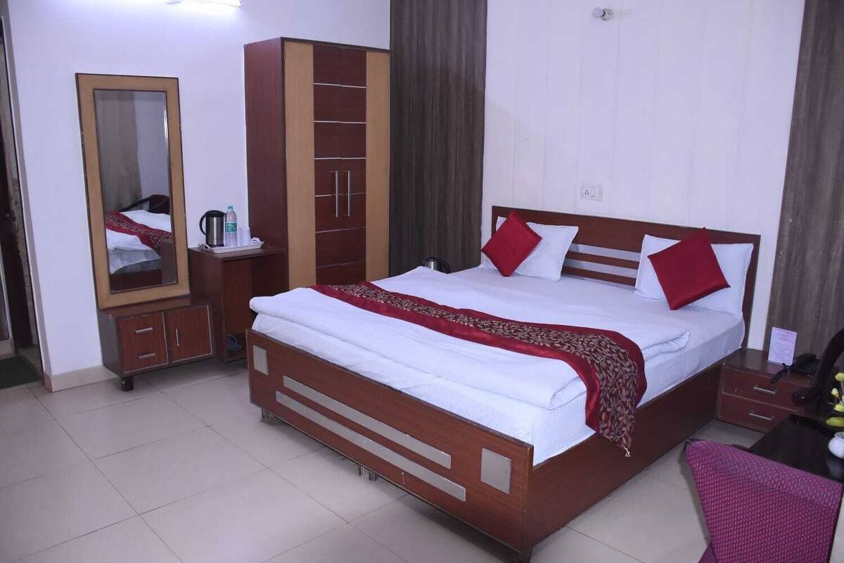 Habitación de hotel con una cama de madera, un espejo, un armario, una mesita de noche y una silla.