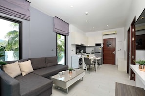 Een modern appartement met een woonruimte, kitchenette en balkon met uitzicht op groen.