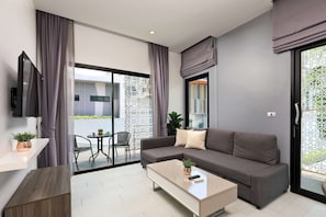 Een moderne woonkamer met een bank, salontafel, televisie en een balkon met planten.